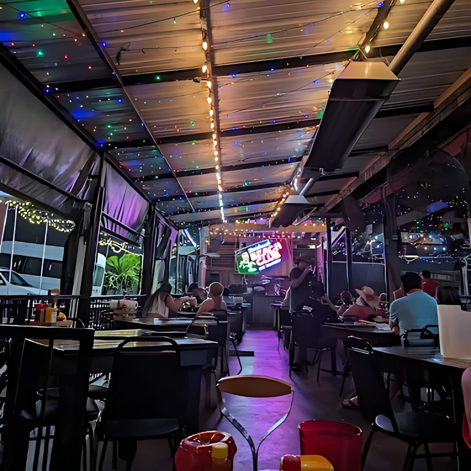 Crazy Alan's Swamp Shack's lively outdoor patio at night, with colorful string lights and patrons dining.
