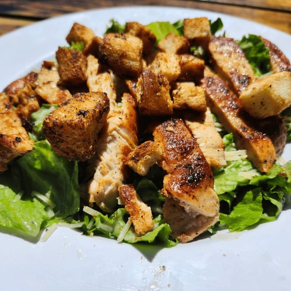 Cajun grilled chicken and croutons on a bed of fresh green lettuce and shredded cheese.