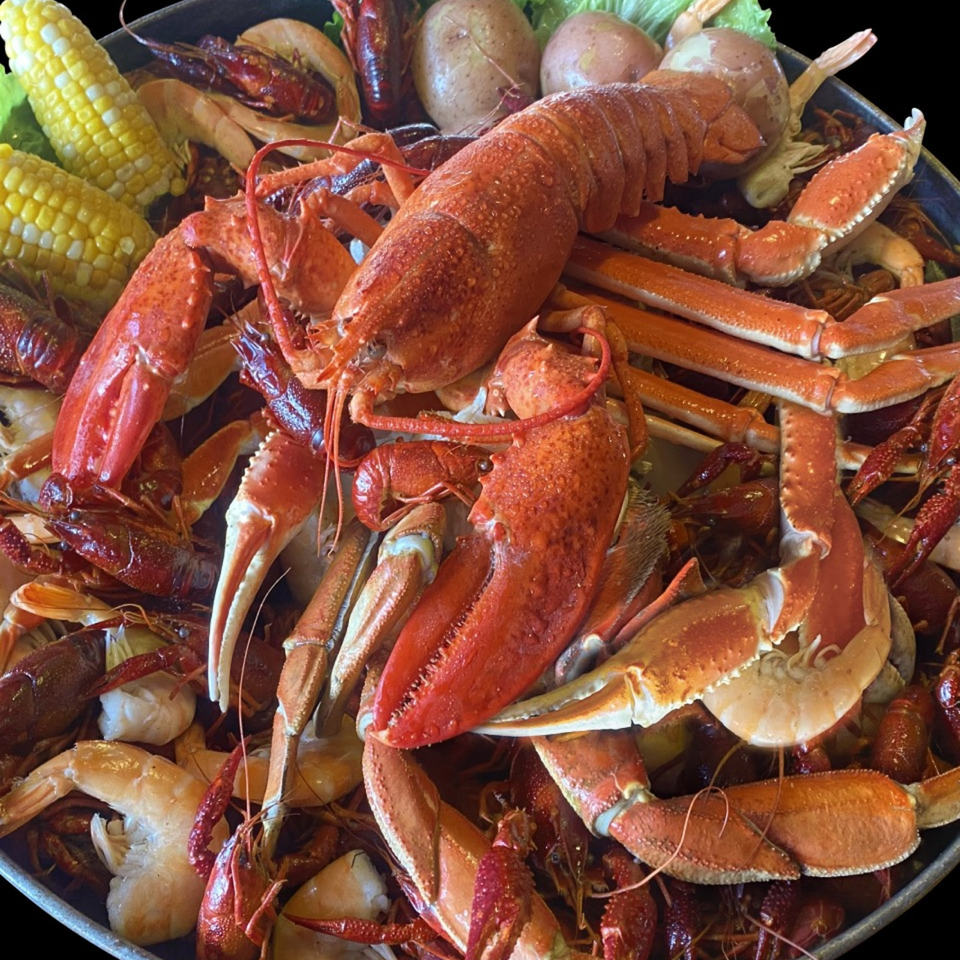 A large Cajun seafood boil with lobster, crab legs, crawfish, shrimp, corn, and potatoes.