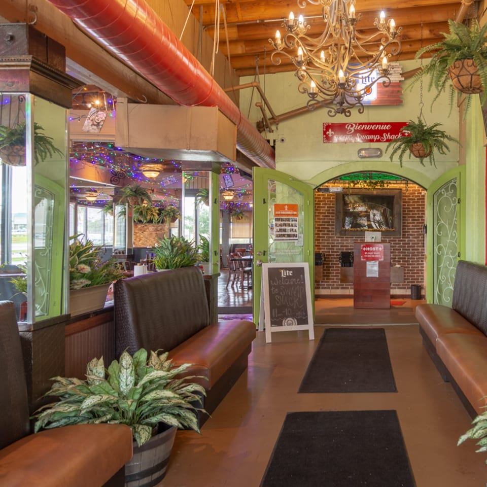 The entrance of Crazy Alan's Swamp Shack, featuring a host stand, seating, and Cajun-themed decor.